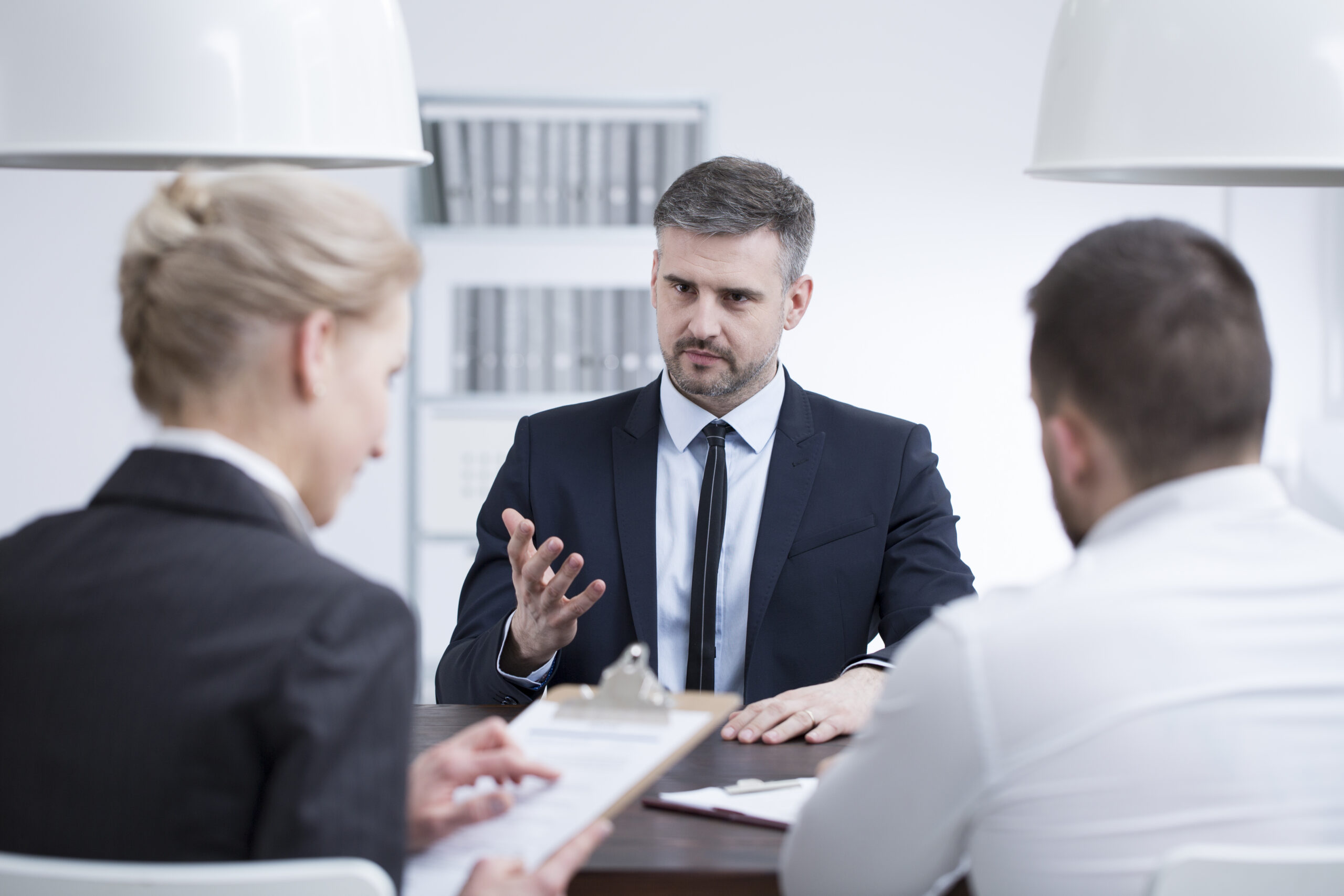 Man in a suit talking about his experience during a job interview in corporation - Tene & Associates